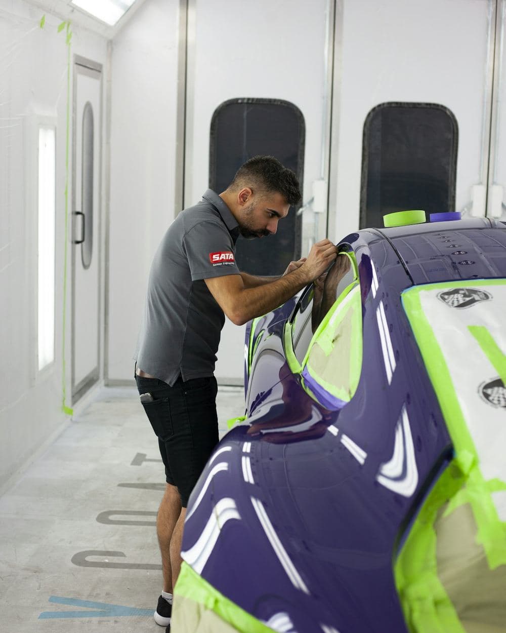 Car masked up inside a lit spray booth